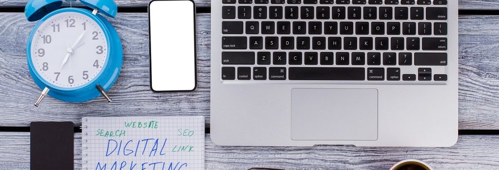 Digital marketing concept flat lay. Laptop with alarm clock and coffee cup.